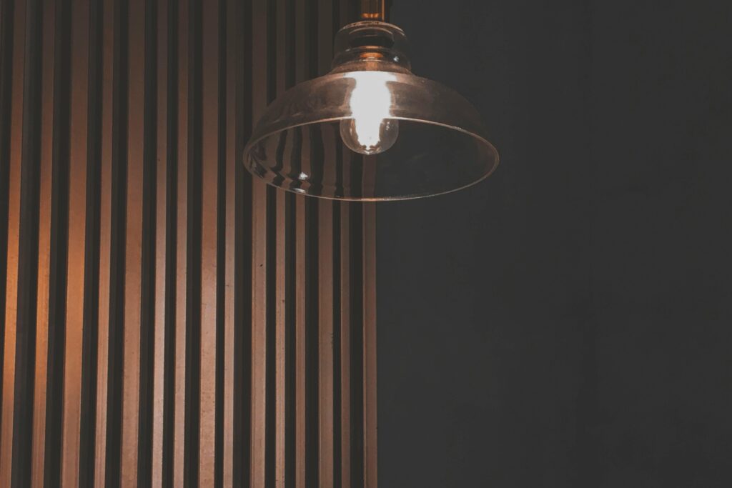 Contemporary pendant light illuminating a wooden panel wall creates a warm, inviting interior atmosphere.