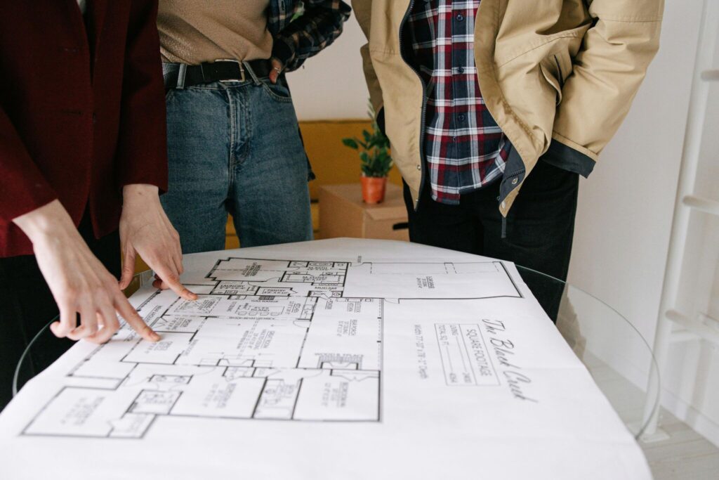 Group of people reviewing a blueprint for real estate planning. Collaborative discussion indoors.